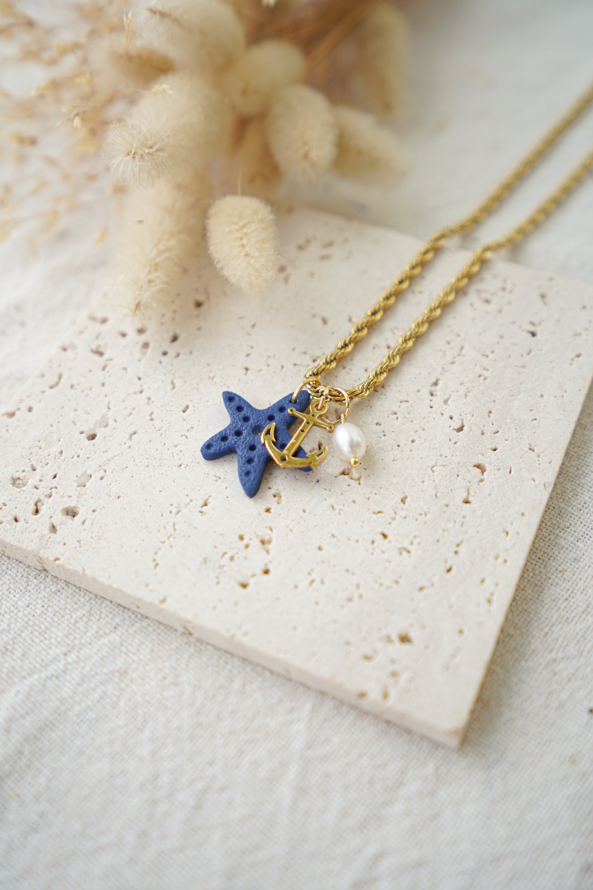 Collar de acero con estrella de mar azul marino, ancla dorada y perla de río