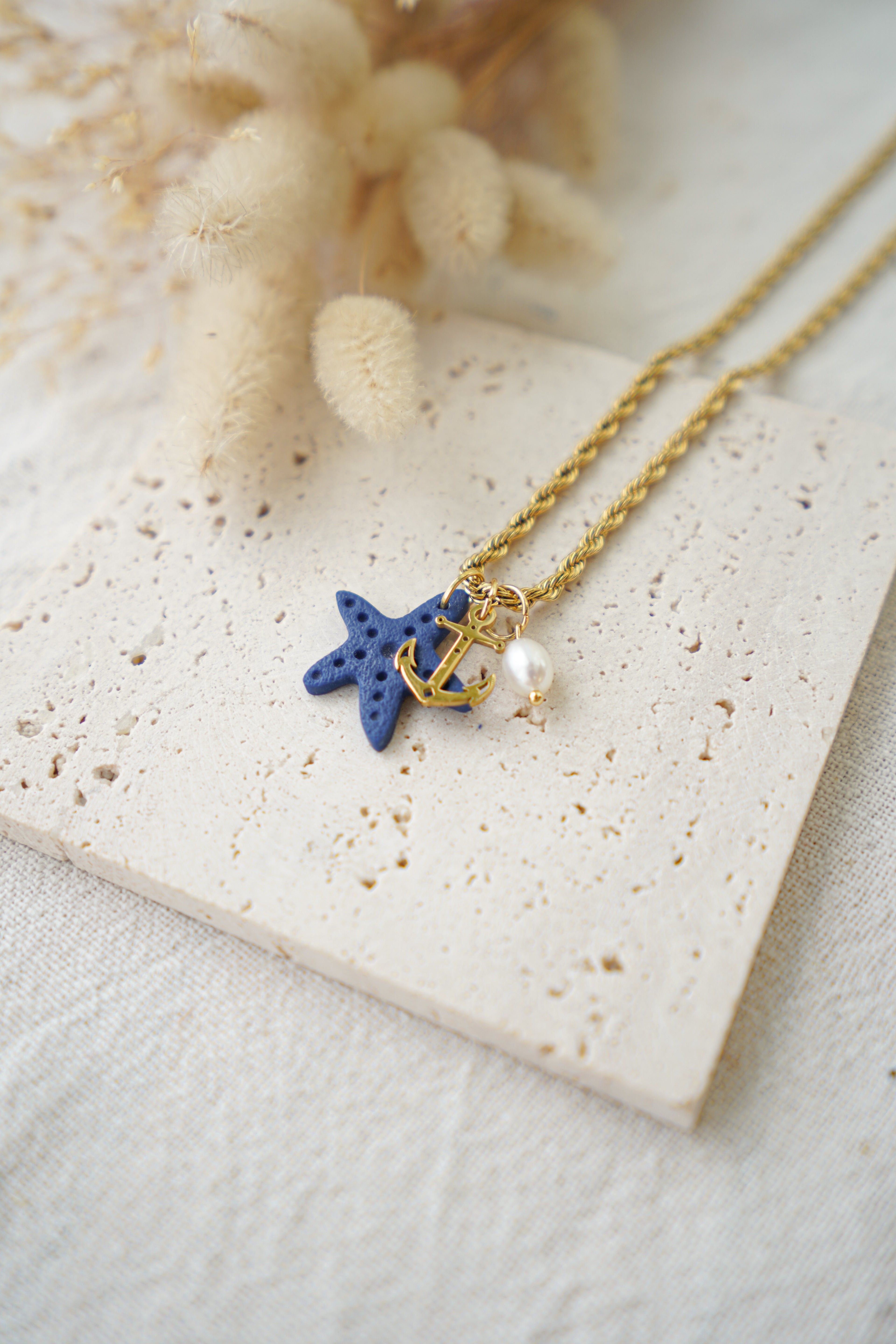 Collar de acero con estrella de mar azul marino, ancla dorada y perla de río
