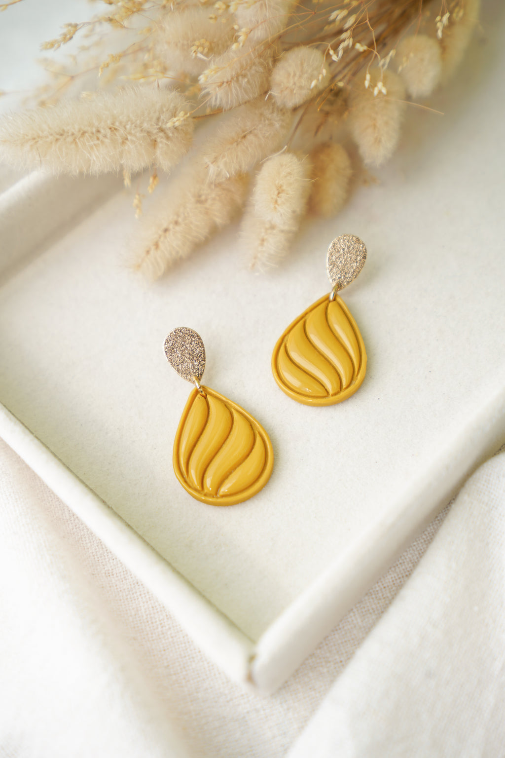 Pendientes Stirling de arcilla polimérica hechos a mano en Galicia, diseño en forma de lágrima con ondas de resina en color amarillo mostaza