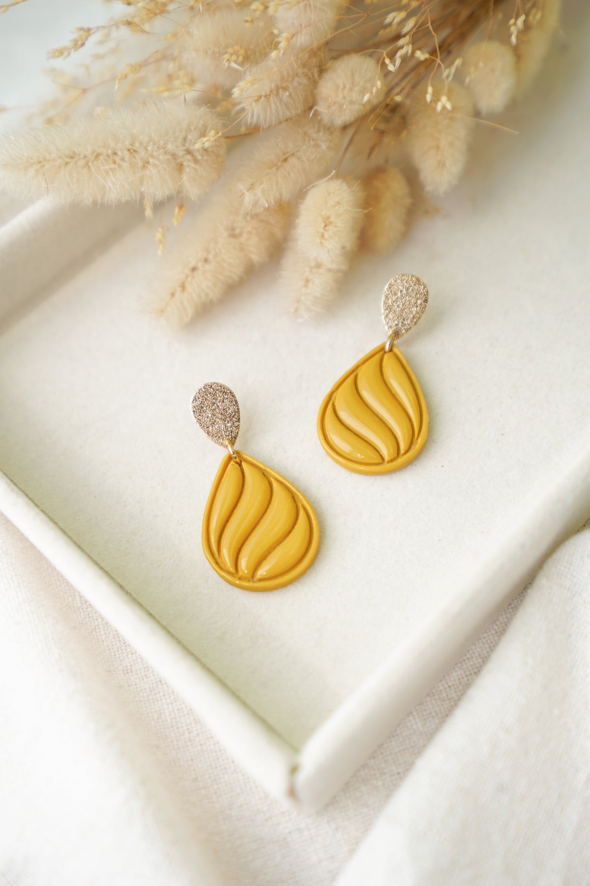 Pendientes Stirling de arcilla polimérica hechos a mano en Galicia, diseño en forma de lágrima con ondas de resina en color amarillo mostaza